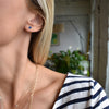 Woman wearing a Birthstone Stud Earring featuring a 4 mm briolette cut Sapphire bezel set in 14k yellow gold