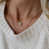 Woman wearing a Greenwich cable chain necklace featuring four 4 mm round opals and one 2.1 mm diamond bezel set in 14k gold