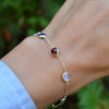 Woman with a Grand 14k yellow gold bracelet featuring 6 mm briolette cut bezel set gemstones