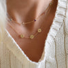 Woman wearing a 14k yellow gold cable chain necklace featuring two 1/4” flat engraved letter discs, spelling XOX
