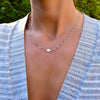 Woman wearing a gold Newport necklace featuring 4 mm briolette cut gemstones and a 1/4” flat letter-engraved disc