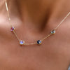 Woman with a Grand 14k yellow gold necklace featuring four 6 mm briolette cut bezel set gemstones