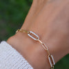 Woman wearing a 14k yellow gold Adelaide paperclip chain pavé bracelet featuring gemstone-encrusted links