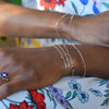 Woman wearing several bracelets including a 14k gold Adelaide mini bracelet featuring 5.2 x 2 mm paperclip chain links