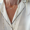 Woman with layered necklaces including a 14k gold necklace featuring three 1/4” flat discs engraved with the letters THH