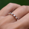 Hand with a Rosecliff stackable ring featuring eleven alternating 2mm garnets and diamonds prong set in 14k yellow gold