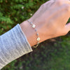 Woman wearing a Newport gold bracelet featuring 4 mm gemstones and 1/4” flat letter-engraved discs