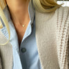 Woman wearing a 14k yellow gold 1.17 mm cable chain Noel necklace featuring one 1/4” flat disc engraved with a snowflake
