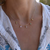 Woman wearing a personalized Providence 5 birthstone drop necklace with petite baguette cut stones set in 14k yellow gold