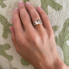 Woman's hand wearing a Warren ring in 14k gold with accent diamonds featuring one 10 x 8 mm emerald cut bezel set white topaz