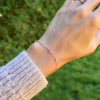 Woman wearing a Pink Awareness Bracelet featuring two Moonstones and one Pink Tourmaline bezel set in 14k yellow gold