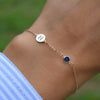 Woman wearing a 14k yellow gold Classic bracelet featuring one sapphire and one 1/4” flat disc engraved with the letter H