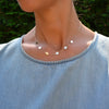 Woman wearing a 14k yellow gold cable chain necklace featuring six 1/4” flat discs engraved with letters