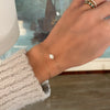 Woman with two bracelets including a 14k yellow gold Classic bracelet featuring one 1/4” flat disc engraved with a heart