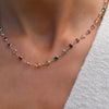 Woman with a Newport necklace featuring alternating 4 mm briolette cut rainbow hued gemstones bezel set in 14k gold