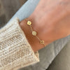 Woman with a 14k gold Classic bracelet featuring three 1/4” flat letter-engraved discs, spelling A-heart-H