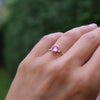 Woman's hand wearing a 1.6 mm wide 14k yellow gold Grand ring featuring one 6 mm briolette cut bezel set pink sapphire