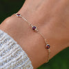 Woman wearing a Bayberry 1.17 mm cable chain birthstone bracelet featuring three 4 mm briolette garnets bezel set in 14k gold