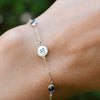 Woman with a 14k yellow gold Classic bracelet featuring two birthstones and 1/4” flat letter-engraved discs