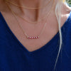 Women wearing layered gold necklaces including a Rosecliff bar necklace with eleven alternating 2 mm rubies & diamonds
