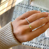 Woman wearing two rings and a Greenwich ring featuring one 4 mm faceted peridot and one 2.1 mm diamond prong set in 14k gold
