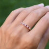 Hand with a Rosecliff stackable ring featuring eleven alternating 2mm round cut rubies and diamonds prong set in 14k gold