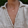 Woman wearing a 14k yellow gold cable chain necklace featuring one 1/4” flat disc engraved with the letter H