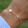 Woman wearing a 14k yellow gold Classic bracelet featuring one moonstone and one 1/4” flat disc engraved with the letter H