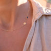 Woman with a 14k yellow gold Classic necklace featuring one sapphire and one 1/4” flat disc engraved with the letter H