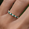 Hand with a Rosecliff stackable ring featuring eleven alternating 2 mm round cut emeralds and diamonds prong set in 14k gold