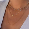 Woman wearing multiple necklaces including a Newport necklace featuring 4 mm briolette cut moonstones bezel set in 14k gold