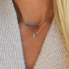Woman wearing two gold necklaces including a Greenwich necklace featuring one 4 mm Nantucket blue topaz & one 2.1 mm diamond