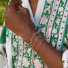 Woman wearing three Newport 14k gold bracelets featuring 4 mm briolette cut bezel set gemstones