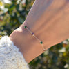 Woman wearing a Noel Bayberry cable chain birthstone bracelet featuring 7 alternating 4 mm emeralds & rubies set in 14k gold