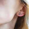 Woman with a Birthstone Stud Earring featuring a 4 mm briolette cut Sapphire bezel set in 14k yellow gold