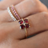 Woman wearing 3 rings including a Greenwich ring featuring four 4 mm rubies and one 2.1 mm diamond prong set in 14k gold