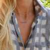 Woman wearing two necklaces including a Rosecliff bar necklace with eleven 2 mm faceted sapphires prong set in solid 14k gold