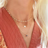 Woman wearing layered necklaces including a 14k gold necklace featuring one 1/4” flat disc engraved with the female symbol